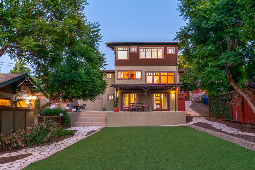 Modern multi-story Craftsman home in North Park San Diego at dusk with mature trees and warm interior lighting
